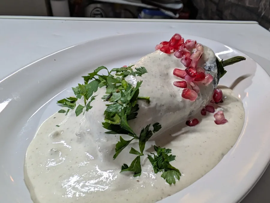 Chile en nogada capeado, cubierto con nogada, granada y hierbas frescas en Sonora's Carbón y Sal.